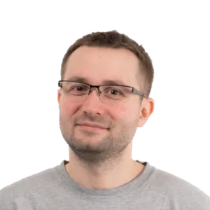 Headshot of a man with short brown hair and glasses wearing a gray t-shirt against a white background.