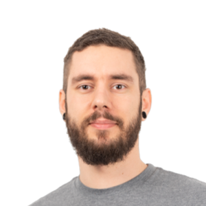 Headshot of a bearded man with short dark hair wearing a gray t-shirt against a white background.