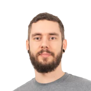 Headshot of a bearded man with short dark hair wearing a gray t-shirt against a white background.