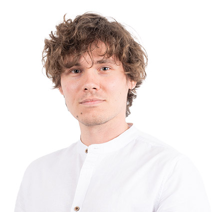 Headshot of a young man with curly brown hair wearing a white button-up shirt against a white background.