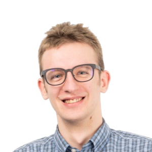 Young man with short blonde hair wearing glasses and a blue checkered shirt, smiling at the camera against a white background.