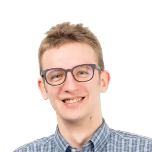 Young man with short blonde hair wearing glasses and a blue checkered shirt, smiling at the camera against a white background.