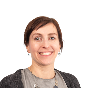 Smiling woman with short brown hair wearing earrings and a dark cardigan over a gray shirt, against a white background.