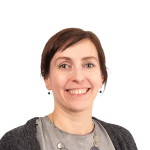 Smiling woman with short brown hair wearing earrings and a dark cardigan over a gray shirt, against a white background.