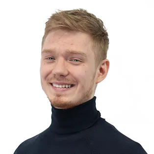 Portrait photograph of a smiling young man with light brown hair wearing a black turtleneck sweater against a white background.