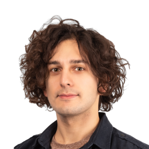 Headshot of a person with shoulder-length curly brown hair wearing a dark navy shirt against a white background
