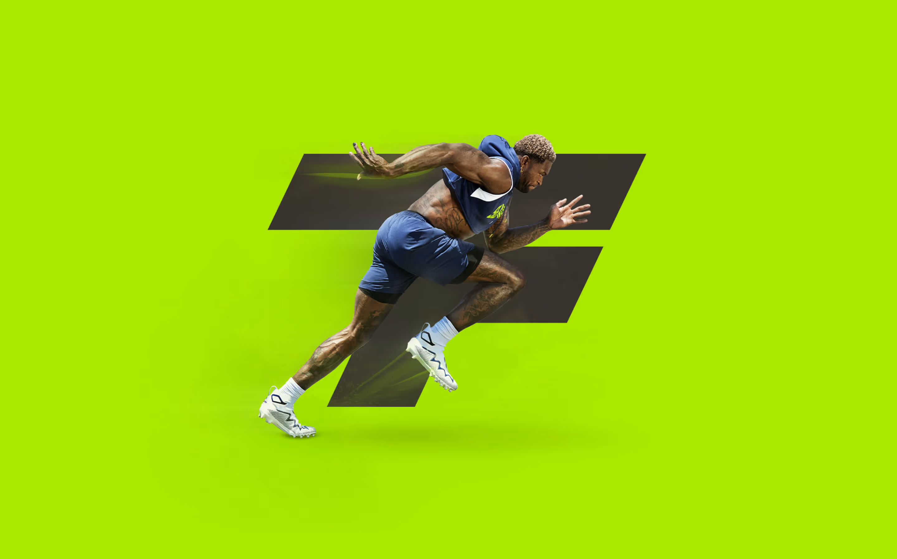 Athlete with vibrant tattoos sprints with intense speed on a lush green track surface.