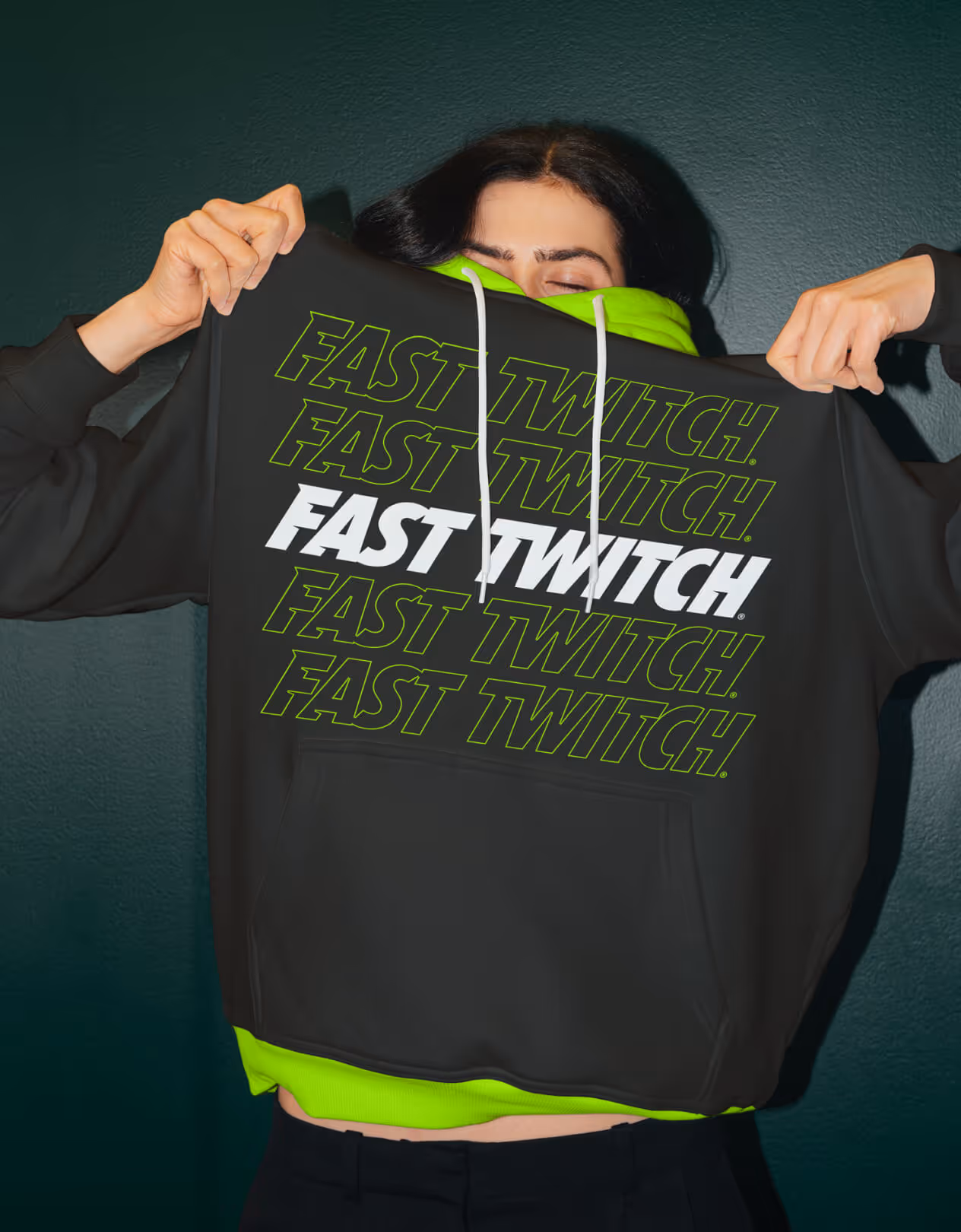 Woman wearing gaming hoodie with neon green and white Fast Twitch logo prominently displayed.