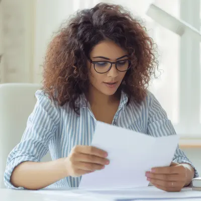Magnifying glass placed over colorful financial reports, symbolizing analysis, review, and attention to detail.