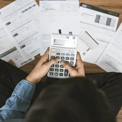 Magnifying glass placed over colorful financial reports, symbolizing analysis, review, and attention to detail.