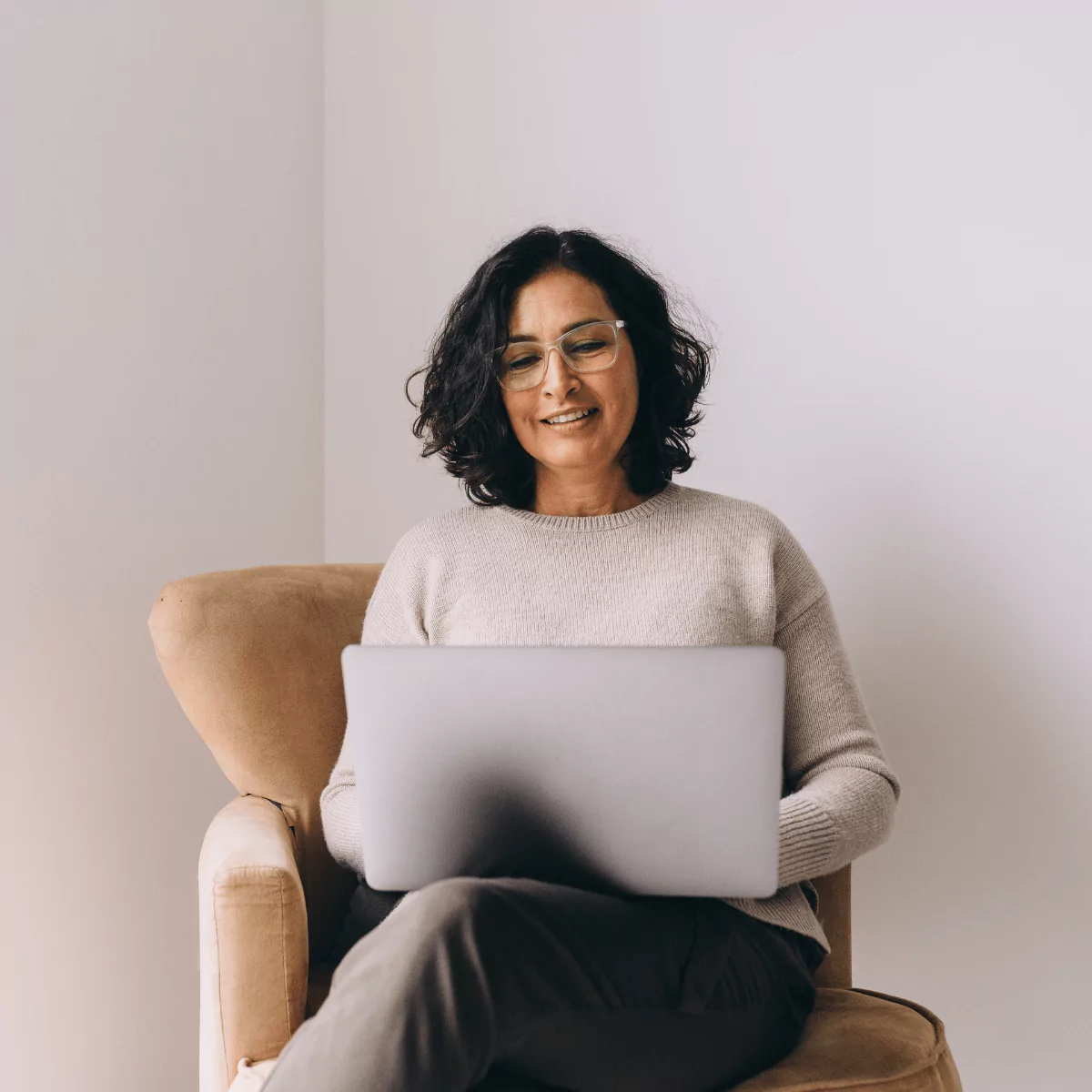 Young woman wearing glasses sitting at a table, reviewing documents with focus, symbolizing organization and financial planning.