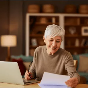Senior woman on the phone, gaining clarity and planning with her laptop and notebook to secure a comfortable retirement.
