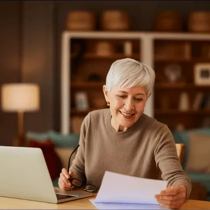 Senior woman on the phone, gaining clarity and planning with her laptop and notebook to secure a comfortable retirement.
