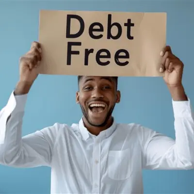 An excited young man holding "debt free" sign illustrating debt freedom after paying off student loans.