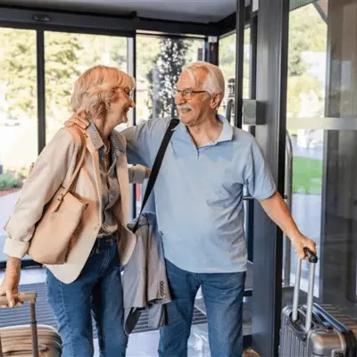 An older couple in a hotel lobby with their luggage, discussing options for reverse mortgage counseling together.  