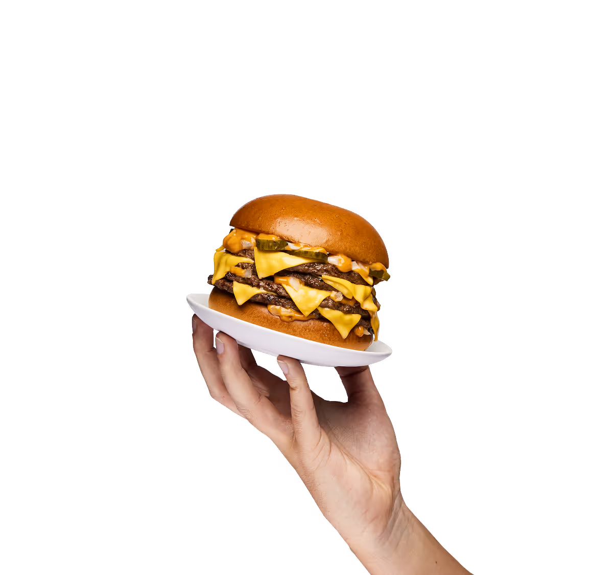 Main tenant une assiette avec un hamburger au fromage à trois étages et des cornichons.