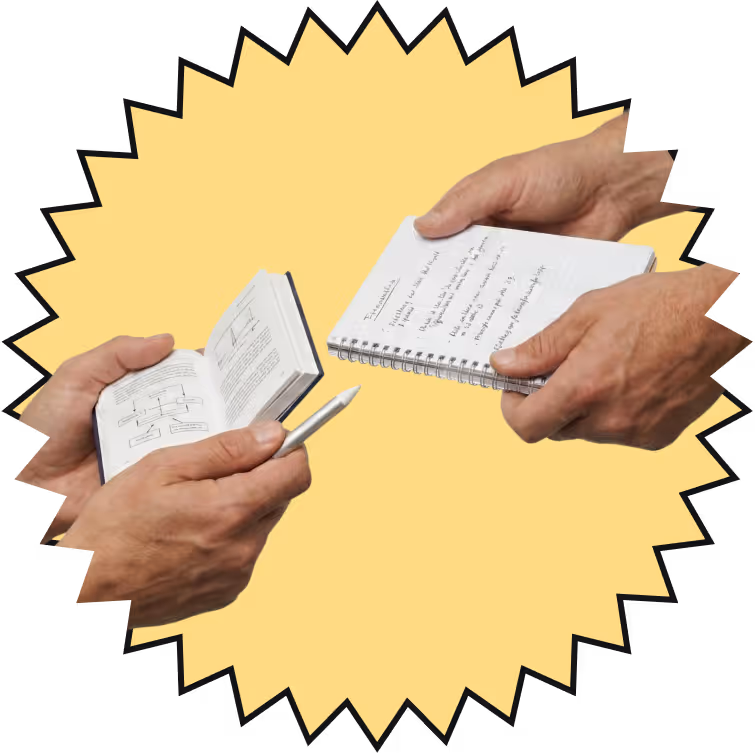 Deux mains tenant des carnets avec des notes écrites, une main tenant aussi un stylo argenté.
