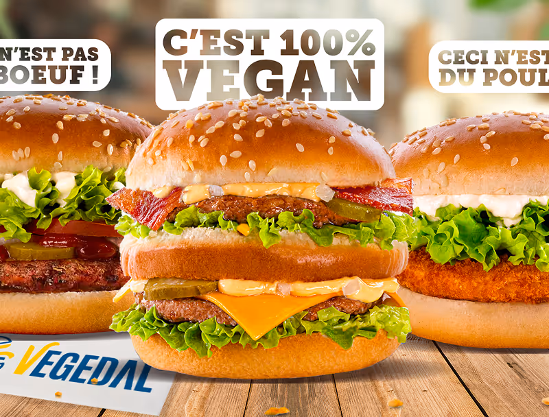 Trois burgers avec du pain aux graines de sésame, laitue, cornichons et sauces, affichant un burger au centre avec un texte indiquant qu'il est 100 % vegan.
