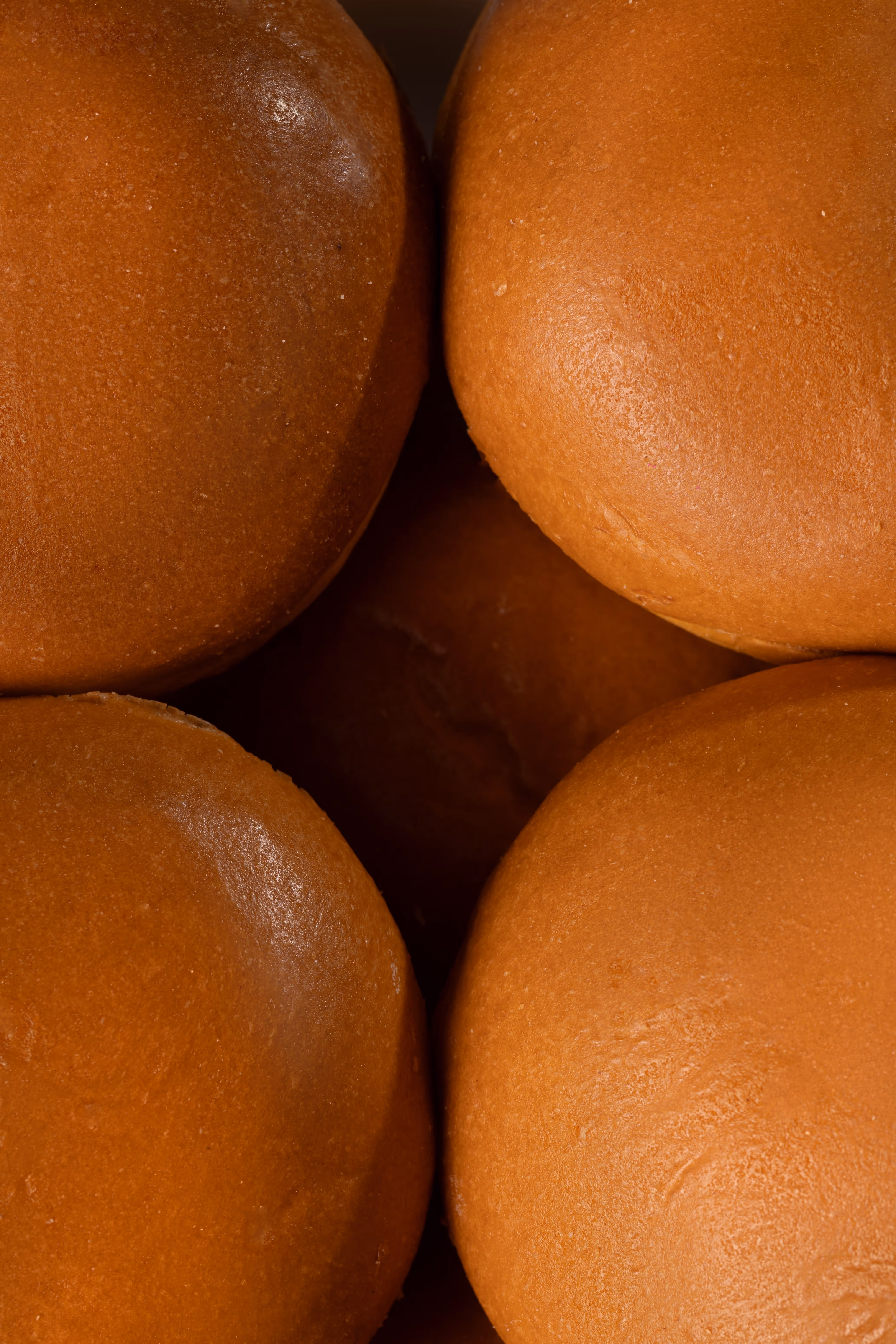 Quatre petits pains à hamburger bruns serrés les uns contre les autres.