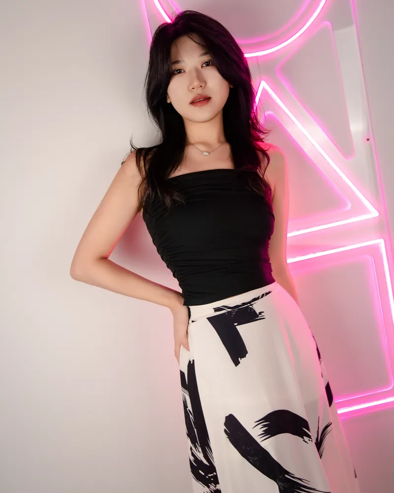 Studio portrait of a woman in front of pink geometric neon lights.