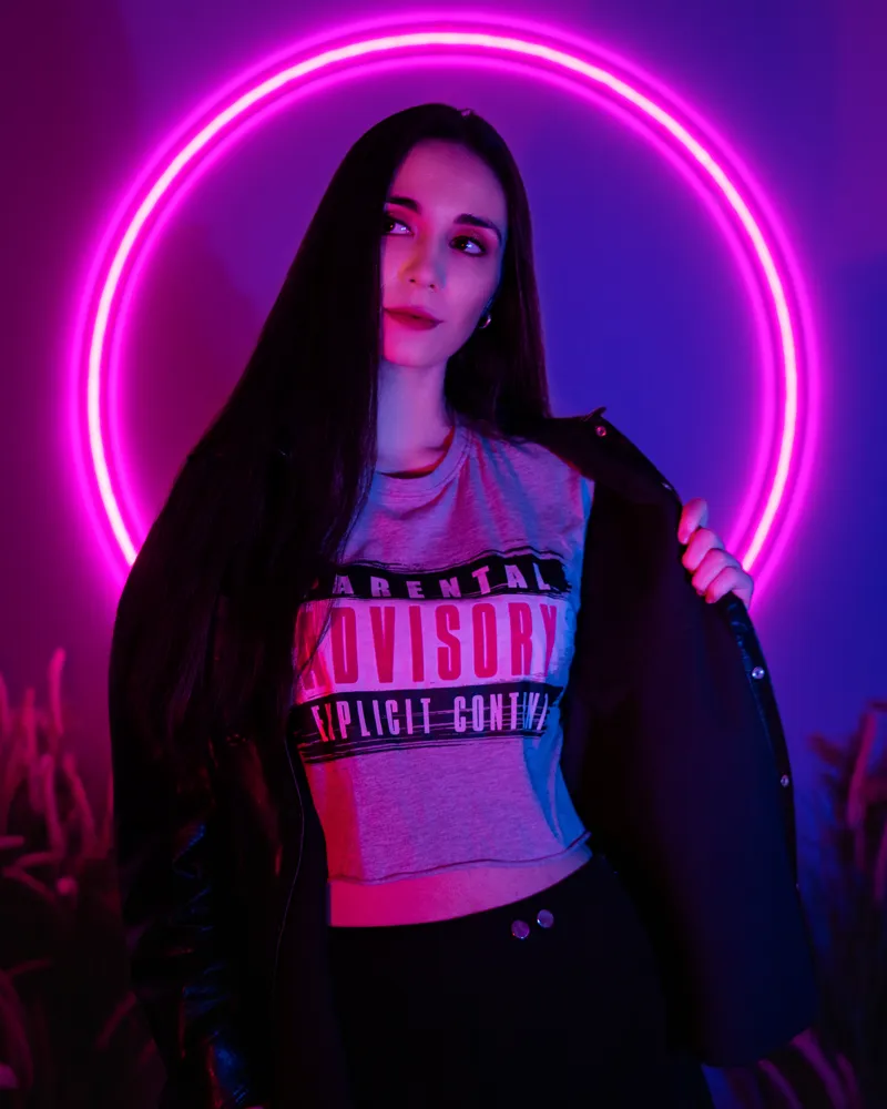 Studio portrait of a woman framed by a glowing pink neon circle.