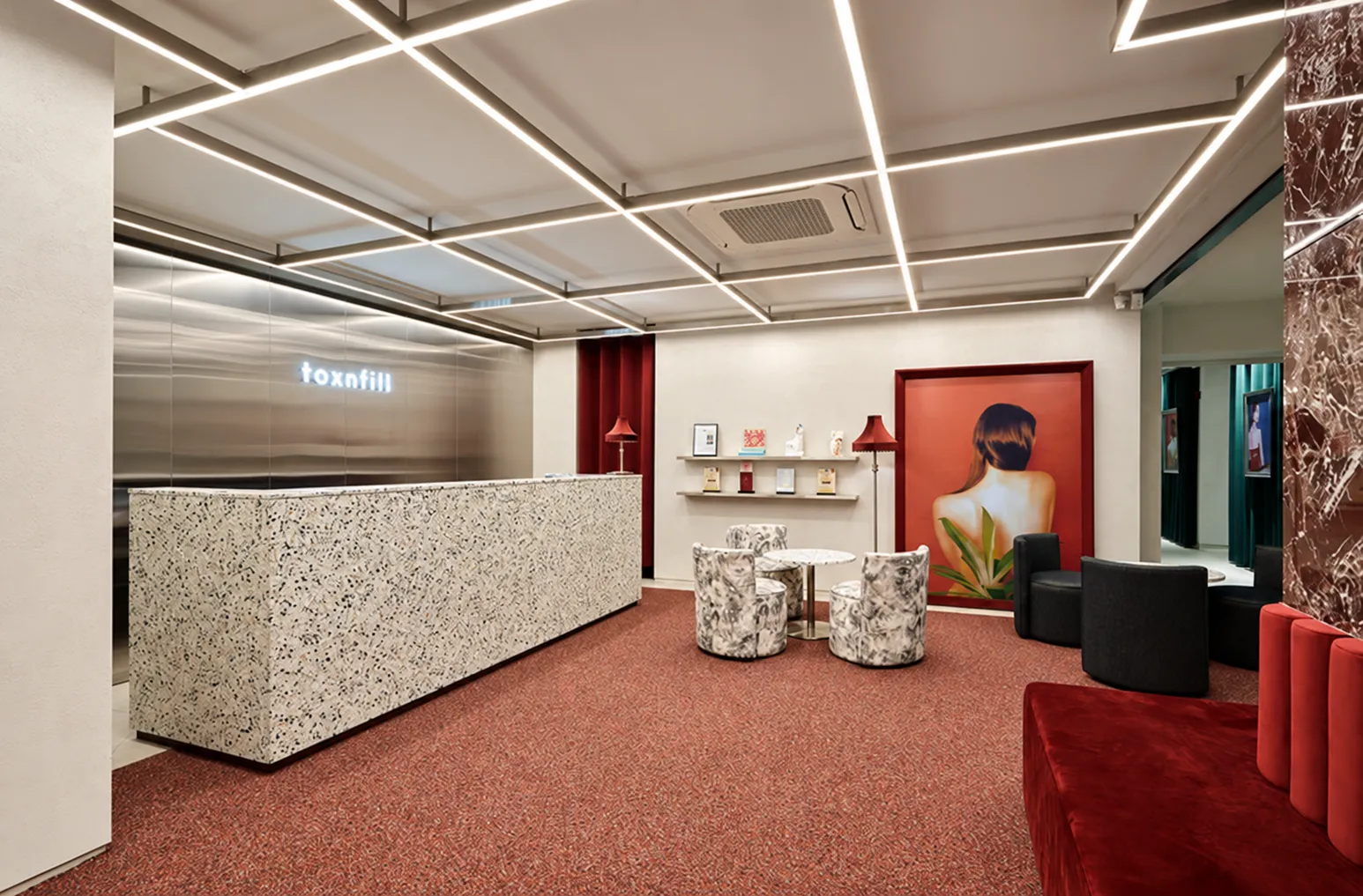 Clinic reception with a stone desk, red seating and ceiling lights. AI-enhanced lighting and color.