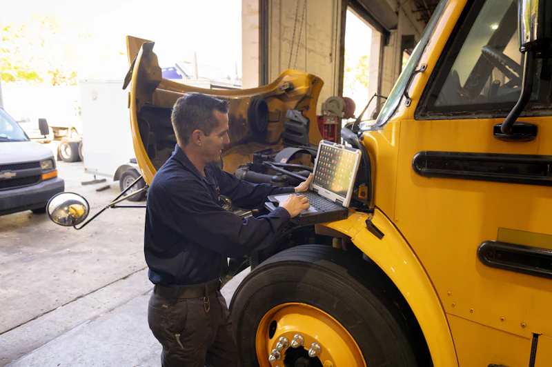 mechanic with a computer with a yellow school bus