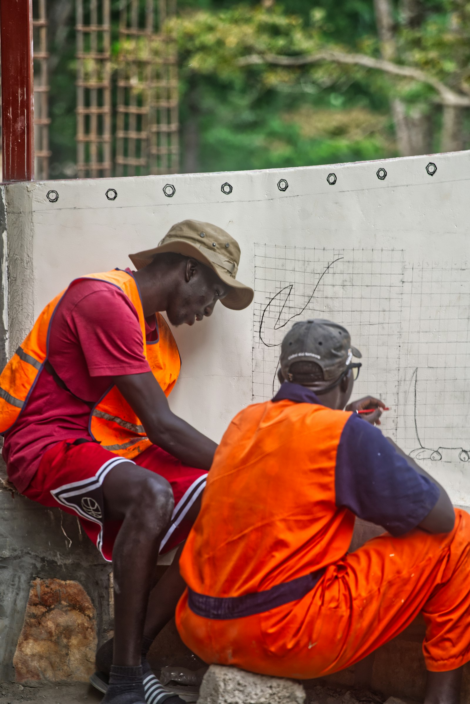 Two construction workers in safety vests reviewing project plans on a building site during inspection