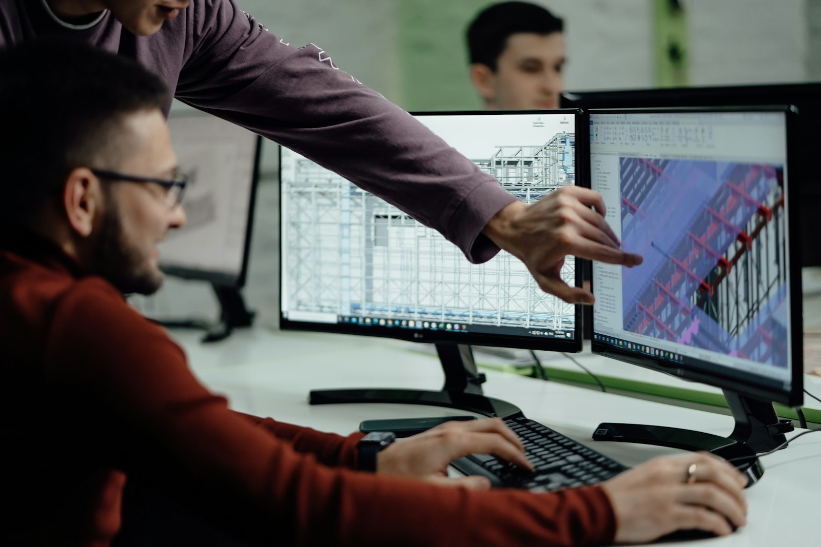 Construction professionals collaborating around computer-aided design drawings while reviewing project documentation in a modern office setting