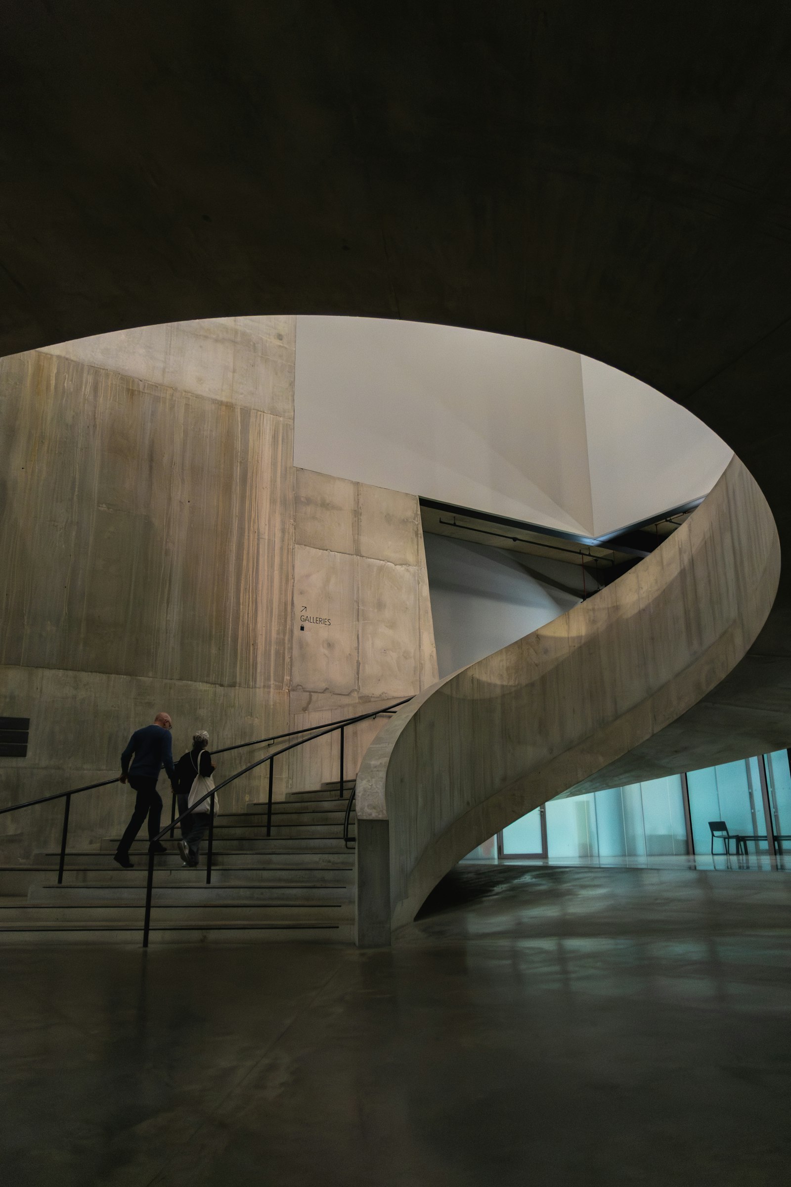 People ascending a concrete spiral staircase in a modern building, evoking scaling AI automation from pilot to enterprise production