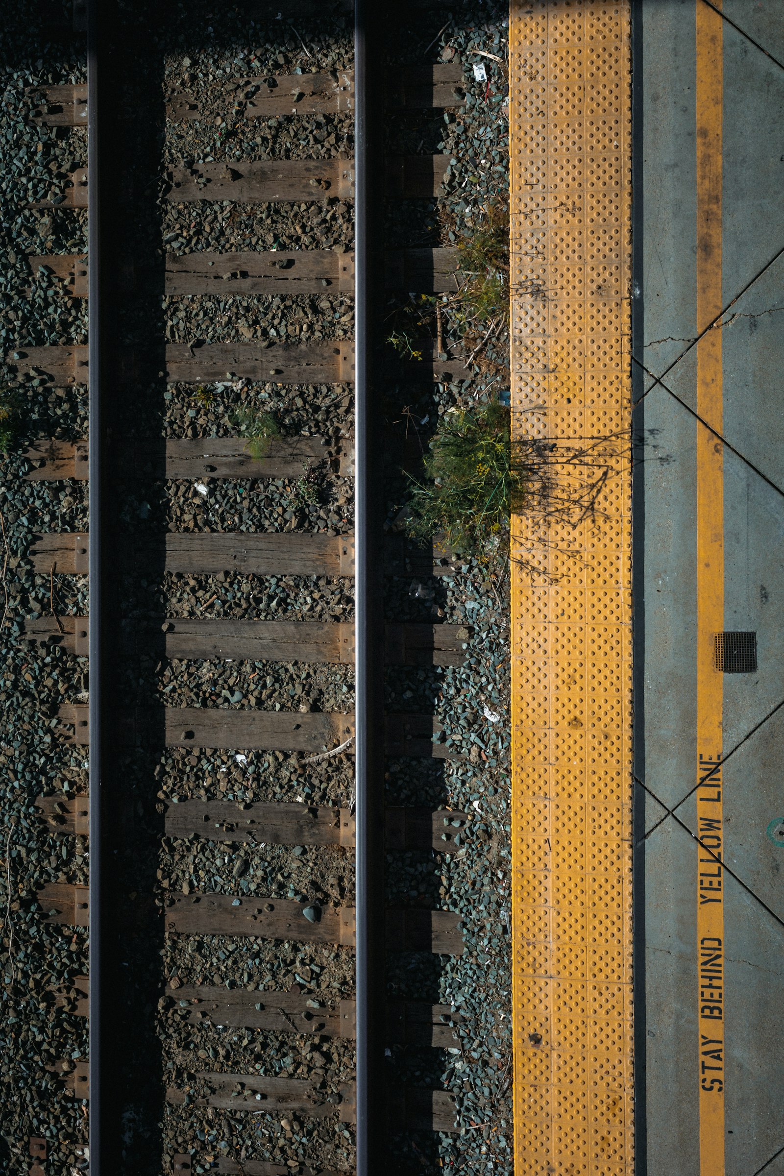 A single railway track curving alongside a yellow line, illustrating the fixed predefined path of workflow automation versus adaptive AI agents.