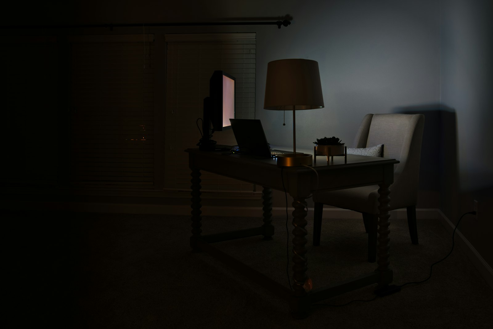 An empty office desk with a laptop and lamp, representing a departing employee's workstation during offboarding.