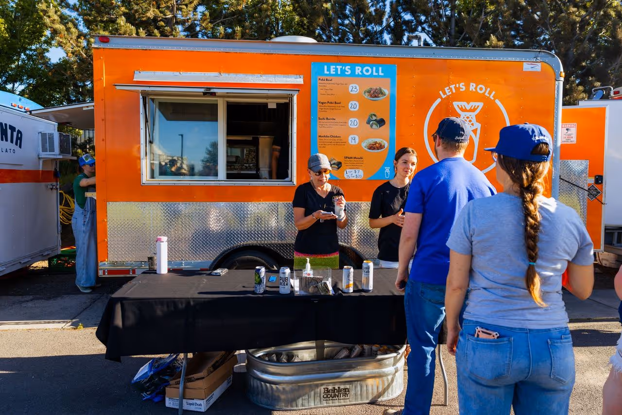 A group of people standing in front of a food truck.