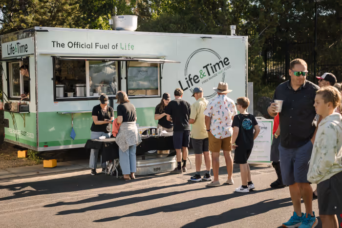 A group of people standing in front of a food truck.