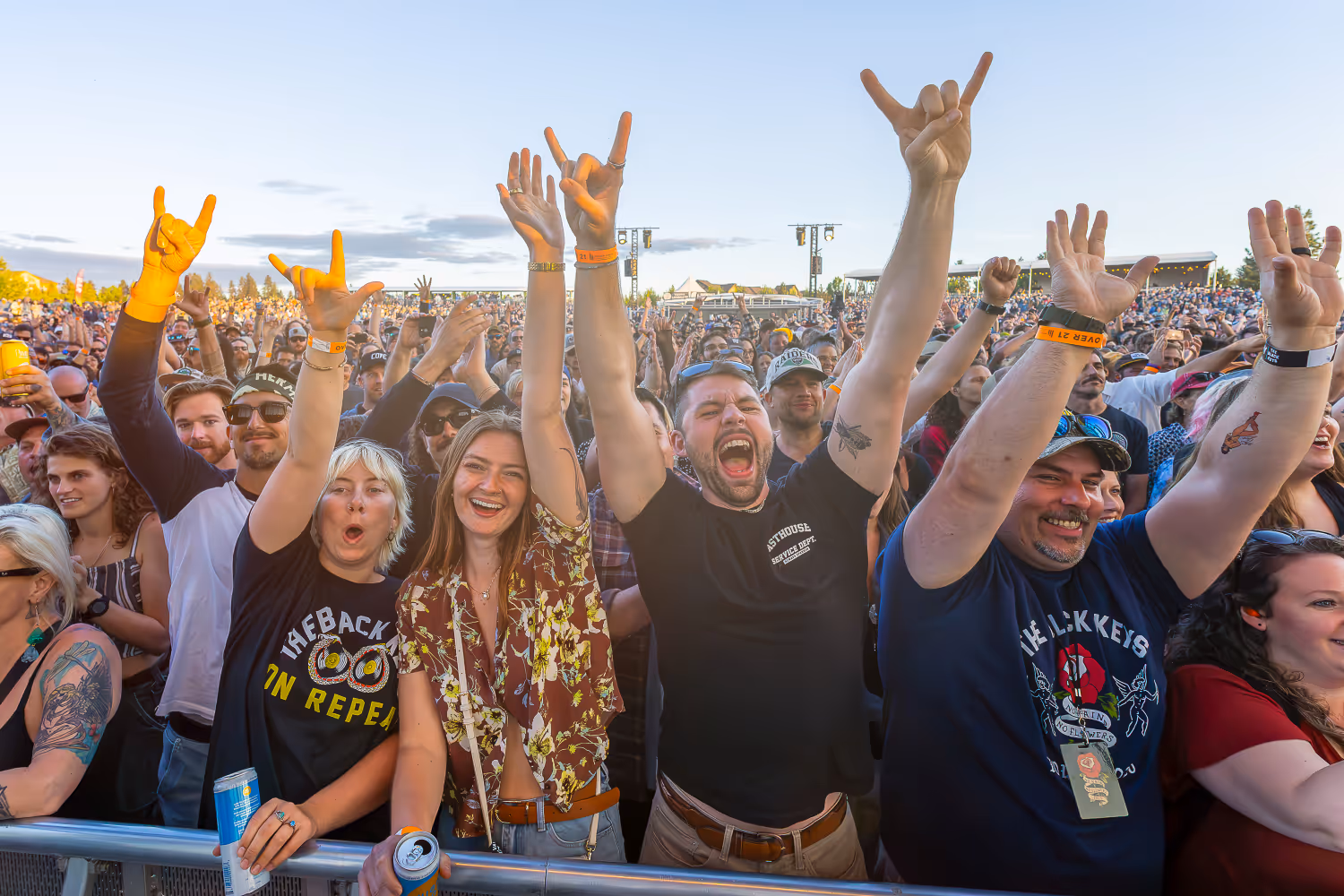 Fans at the barricade at the Black Keys concert at Hayden Homes Amphitheater in Bend, Oregon cheering loud with hands in the air.