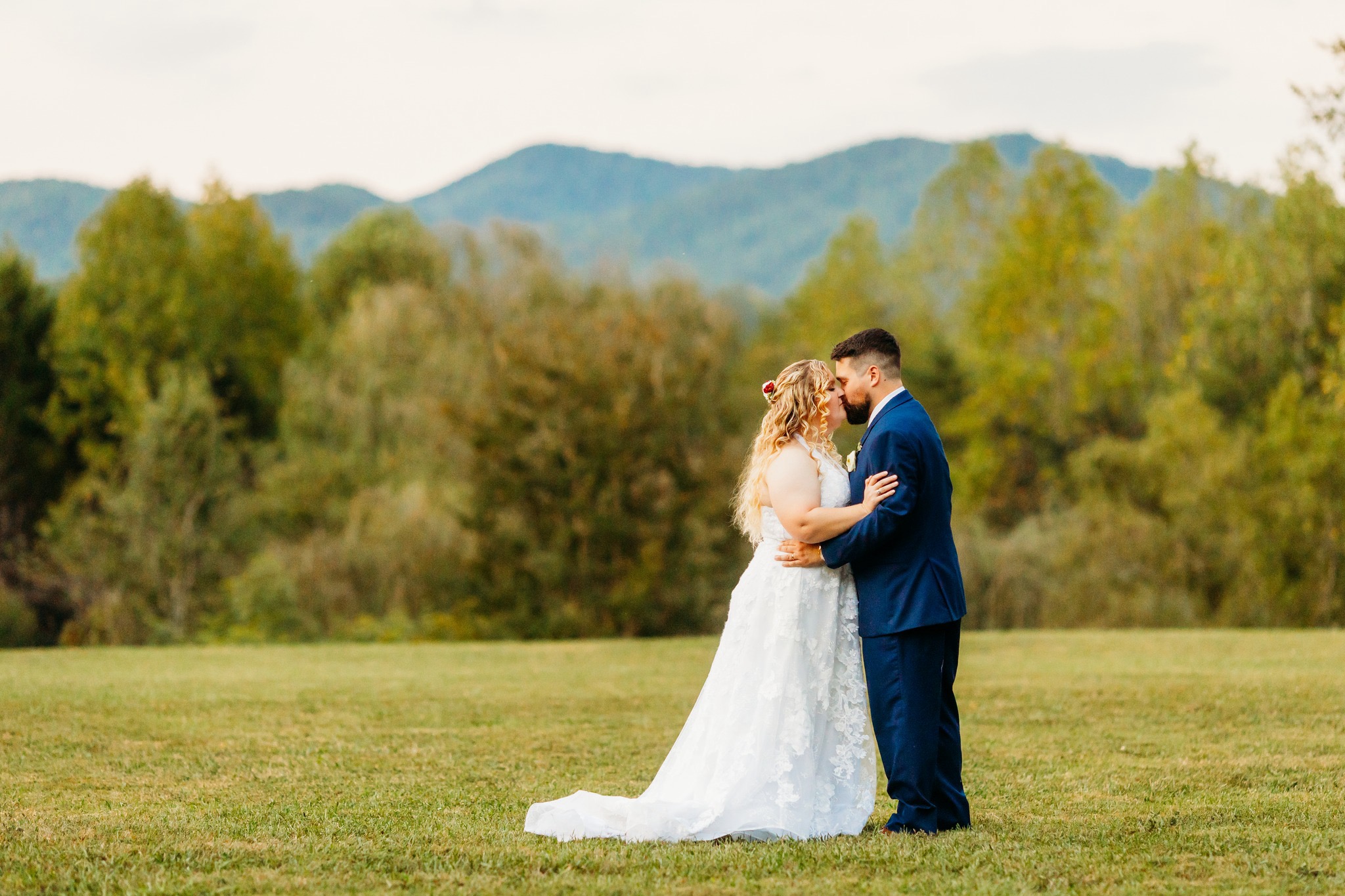 A newly wedded couple kissing in the smokey mountains.
