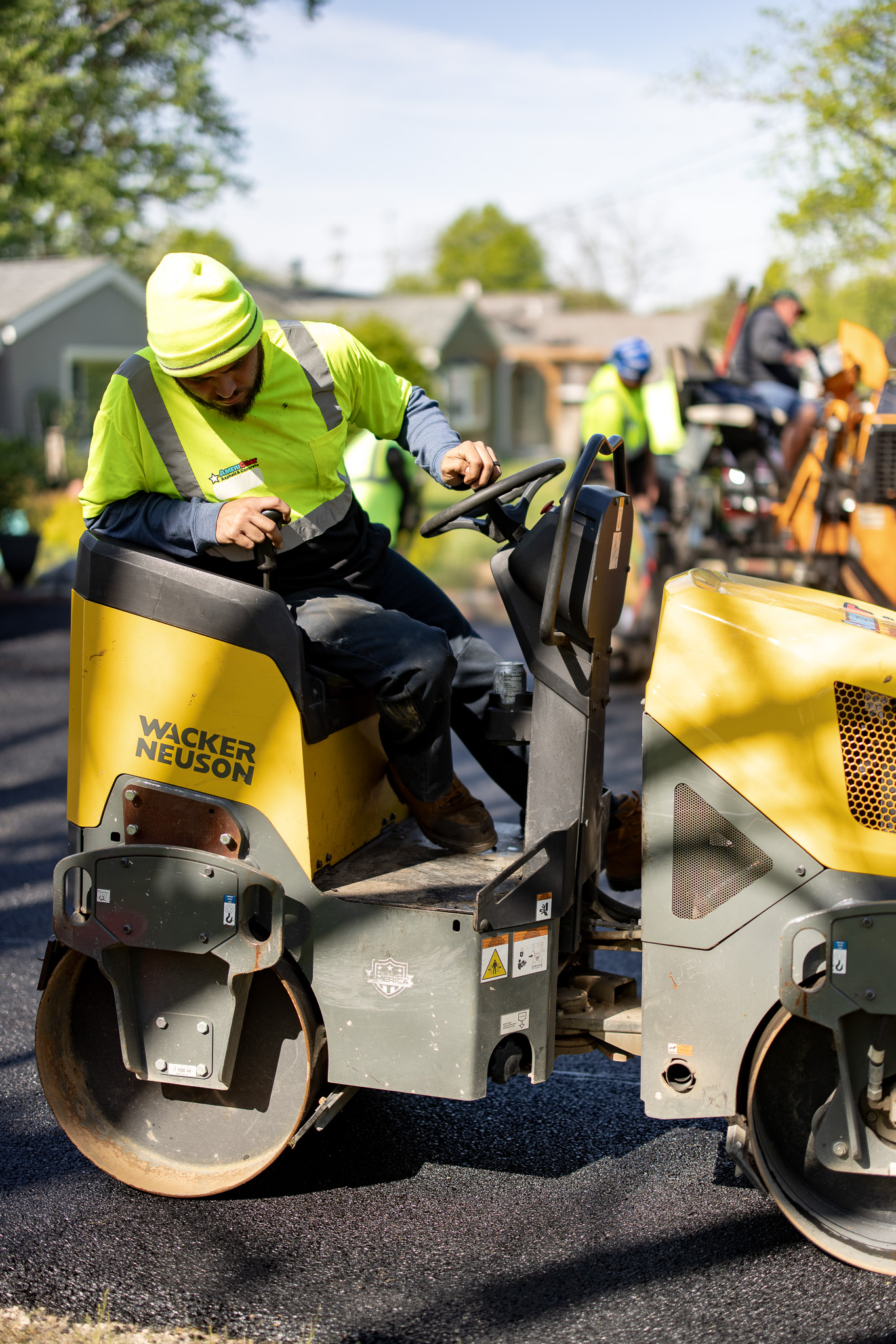 AmeriCoat technician operating asphalt roller compactor on residential driveway paving project in Central Ohio