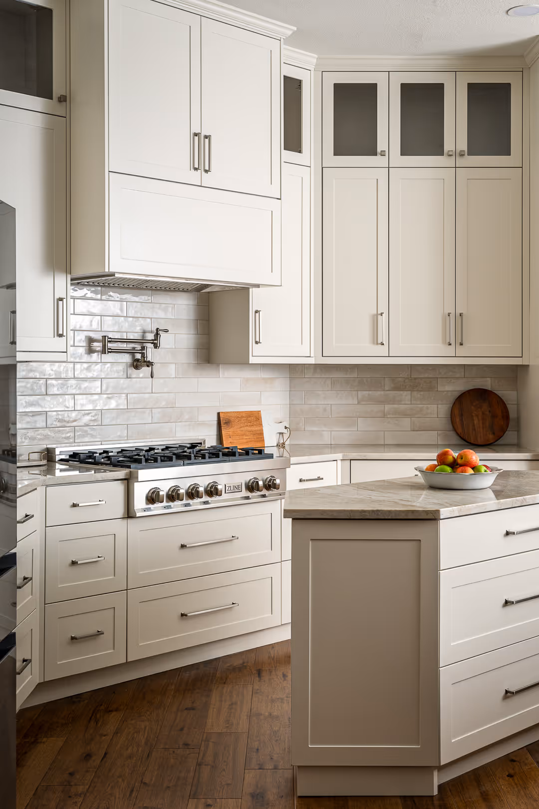 Modern kitchen remodel with white cabinetry, a stainless steel gas stove, marble-topped island, in Cedar Park, TX.