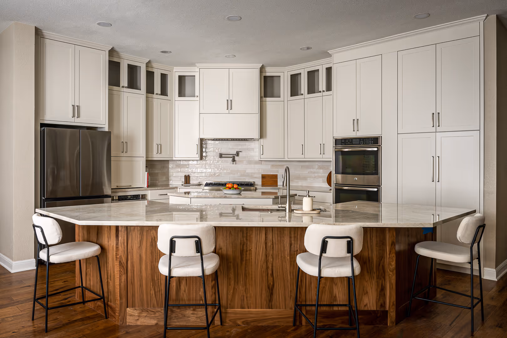New remodeled kitchen with white upper cabinets, stainless steel appliances, a marble countertop island with wood paneling, in Cedar Park, TX.