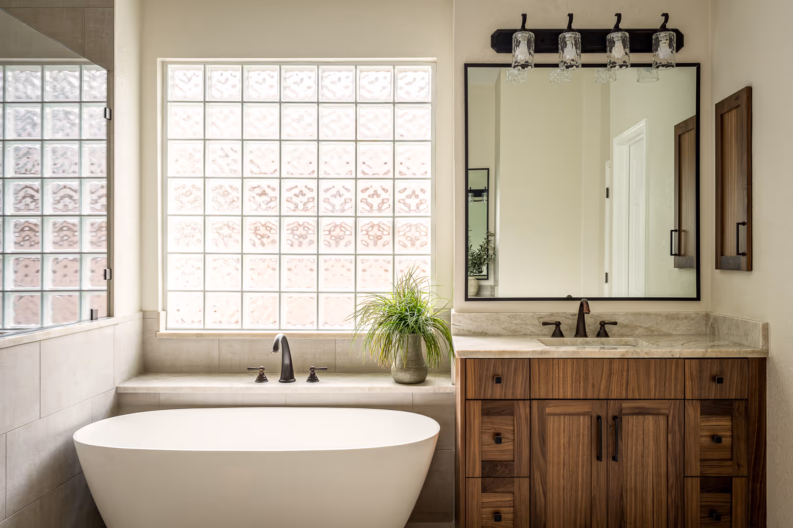 Modern bathroom remodel with a white freestanding bathtub, wooden vanity with marble countertop, large square mirror, in Cedar Park, TX.