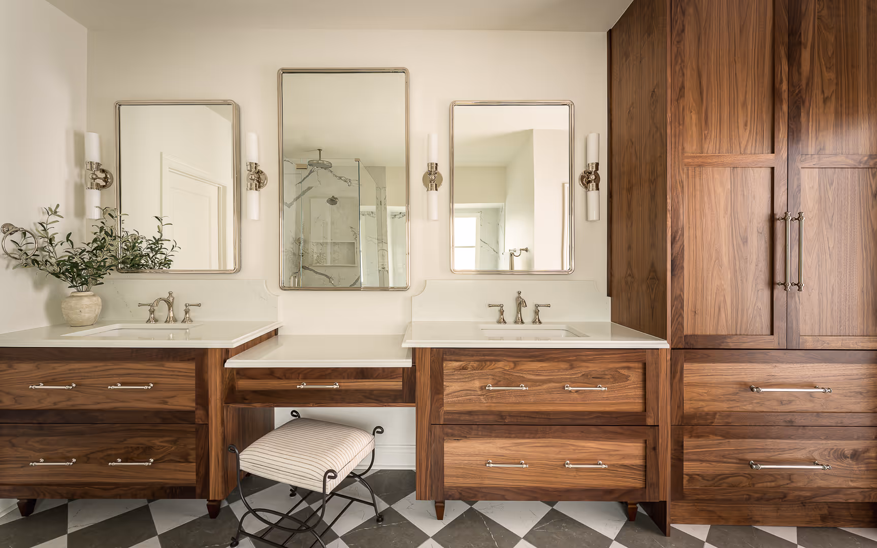 Modern bathroom remodel with vanity with two sinks, three mirrors, wooden cabinetry, and a striped cushioned stool on a checkered floor, Tarrytown, Austin.
