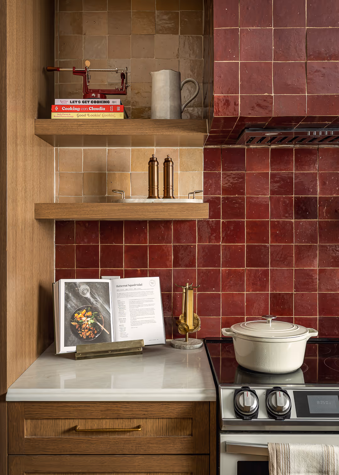 Recently remodeled kitchen with a corner with wooden shelves holding cookbooks, and a  stove with red tiled backsplash in South Austin.