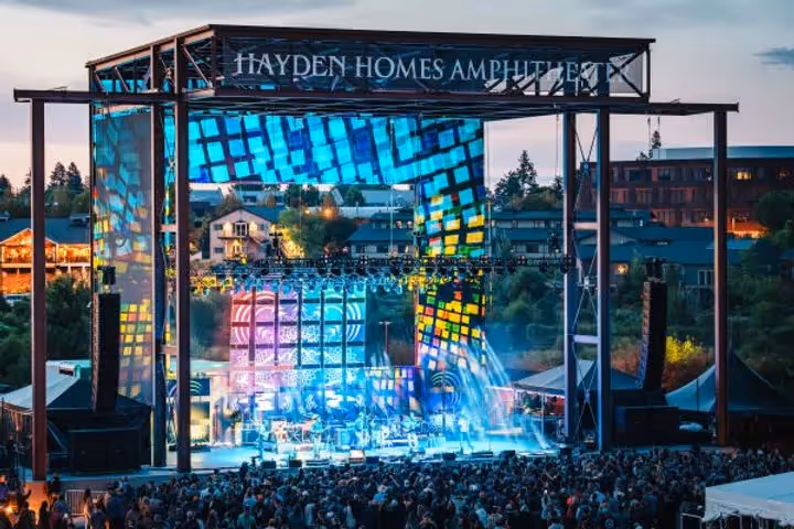 Photo of multicolored stage of Hayden Homes Amphitheater while bluegrass band Yonder Mountain String Band performs