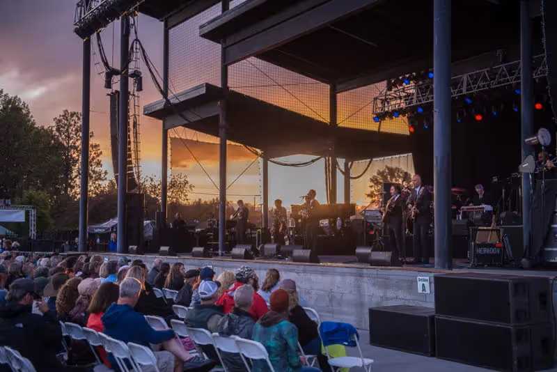 Lyle Lovett performing as the sun goes down and a storm rolls in