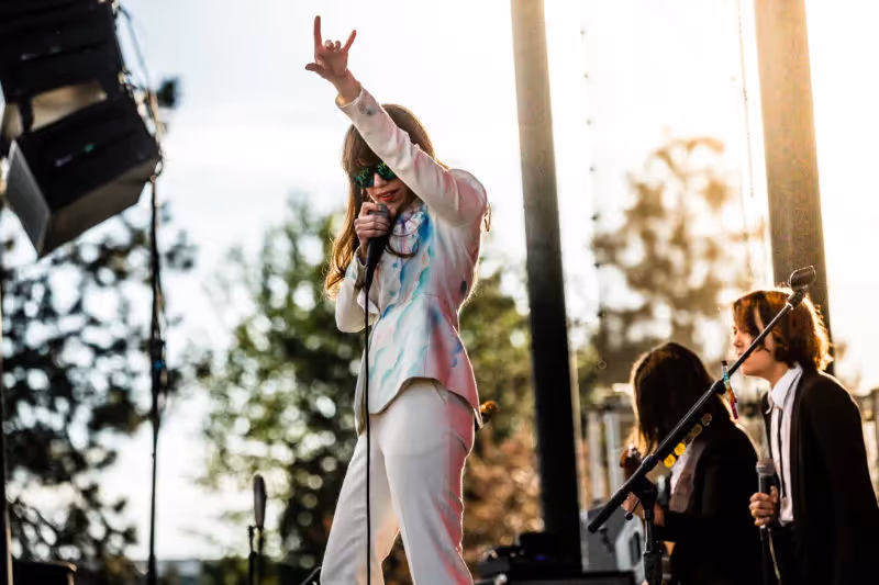 Photo of Jenny Lewis in a white power suit performing in 2015