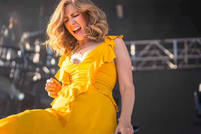 Rachael Price of Lake Street Dive singing in a yellow dress during their 2019 performance