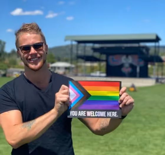 Photo of person holding all are welcome here sign