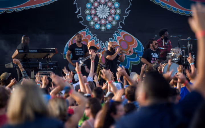 Photo of Trombone Shorty performing when the stage had the crow mural in the background