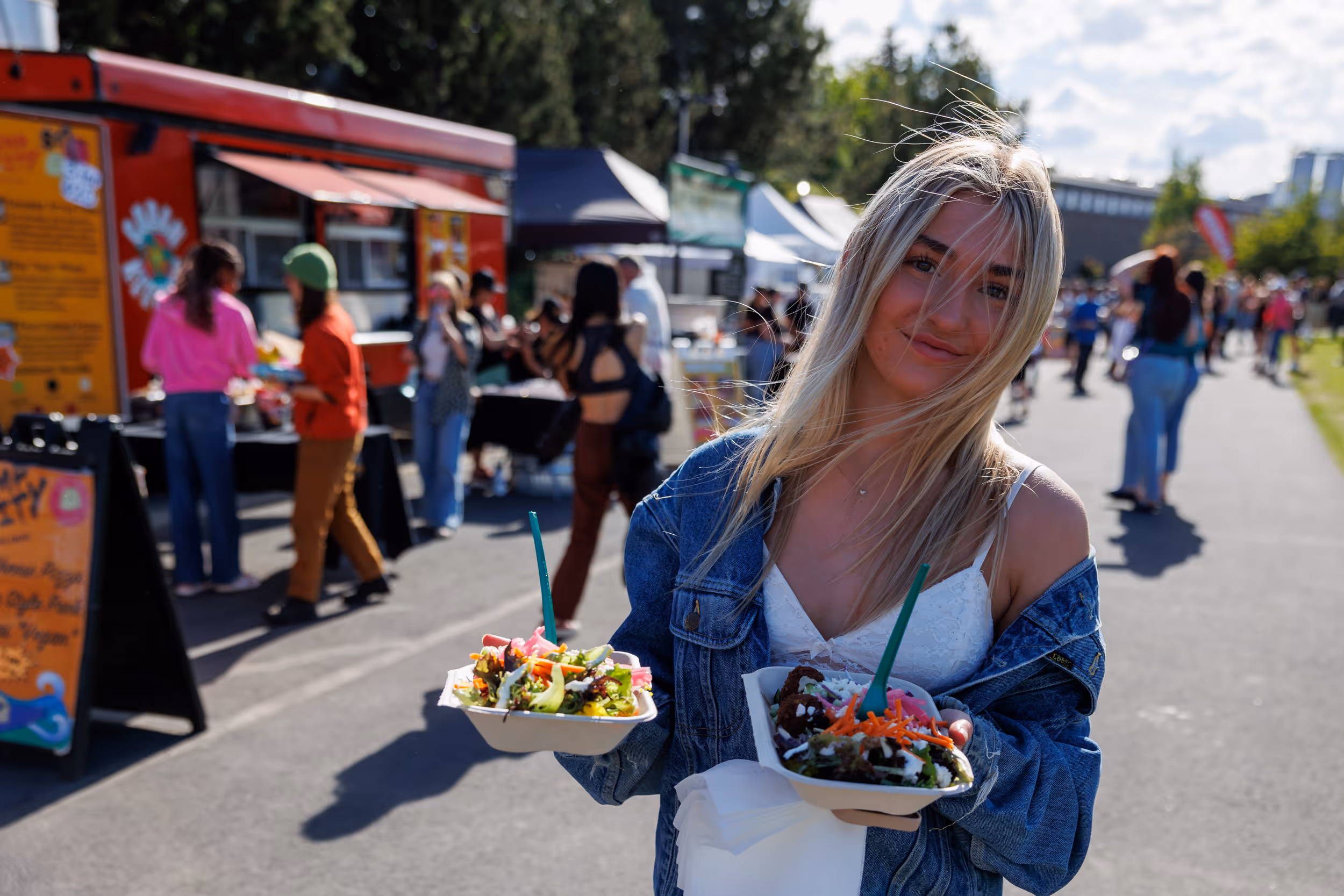 Gal at Hayden Homes Amphitheater holding two plates of delicious food from Food Vendor Row at the venue