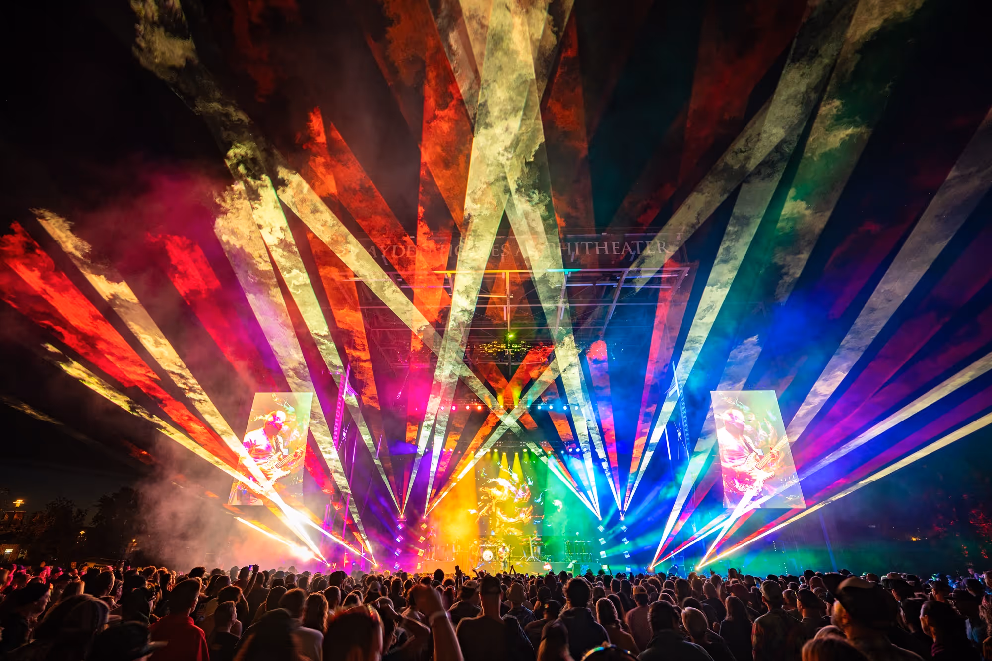 The stage of Hayden Homes Amphitheater in Bend, Oregon lit up by rainbow color laser display.
